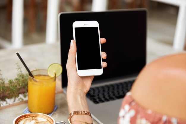 Primer plano de la mano de la mujer que sostiene el teléfono inteligente con espacio de copia en blanco