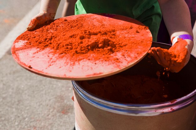 Primer plano de la mano de la mujer que toma polvo de color holi del tambor