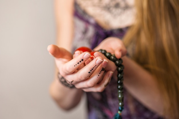 Primer plano de la mano de una mujer sosteniendo bolas chinas rojas y cuentas espirituales