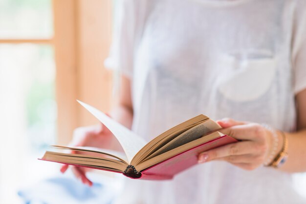 Primer plano de la mano de la mujer sosteniendo el libro rojo