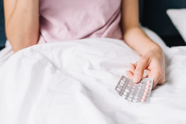 Primer plano de la mano de la mujer sosteniendo la píldora paquete de ampolla