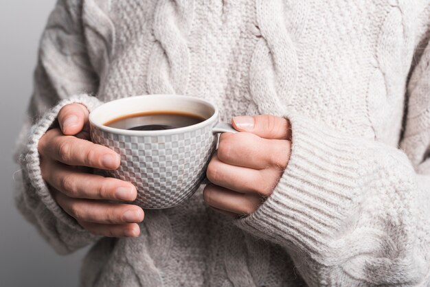 Primer plano de la mano de mujer sosteniendo una taza de café