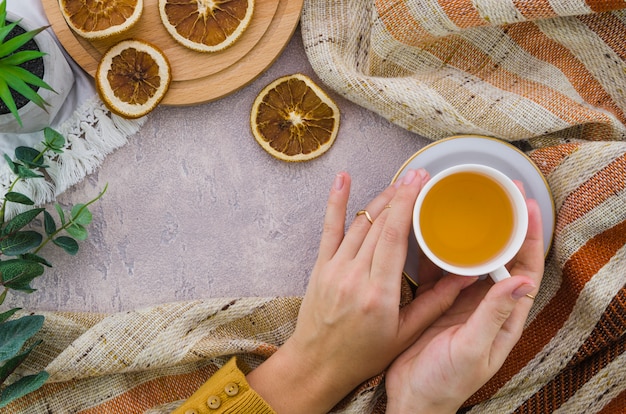 Primer plano de la mano de una mujer sosteniendo la taza de té de hierbas y té de limón seco