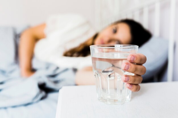 Primer plano de la mano de la mujer tomando un vaso de agua