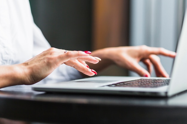 Primer plano de la mano de una mujer usando la computadora portátil