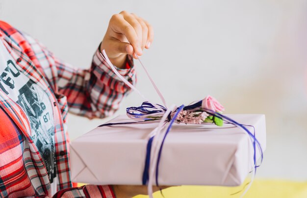 Primer plano de la mano de una niña desenvolver el regalo de cumpleaños