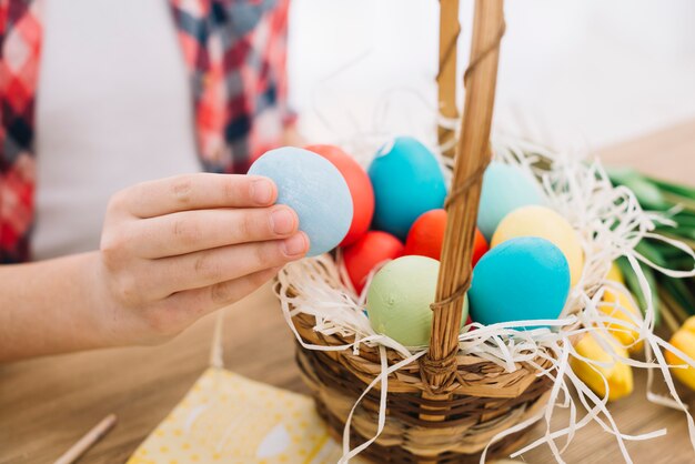 Primer plano de la mano de una niña sosteniendo el huevo de Pascua azul