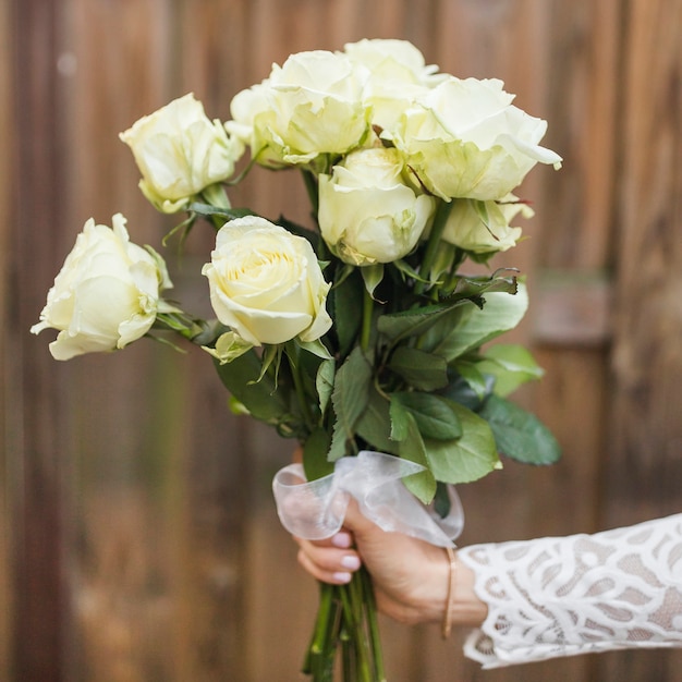 Primer plano de la mano de la novia con ramo de rosas