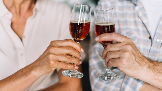Primer plano de la mano de la pareja senior tostado copas de vino