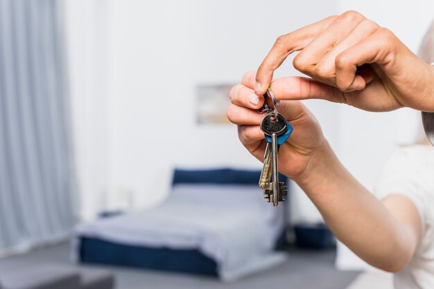 Primer plano de la mano de la pareja sosteniendo las llaves de la casa en el dormitorio