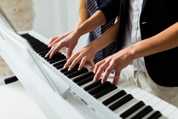 Primer plano de la mano de la pareja tocando el teclado del piano