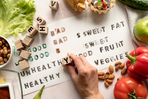 Foto gratuita primer plano de la mano de una persona que imprime texto no saludable en papel con alimentos y bloques