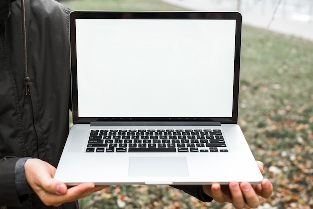 Primer plano de la mano de una persona que muestra una tableta digital con pantalla blanca en el exterior