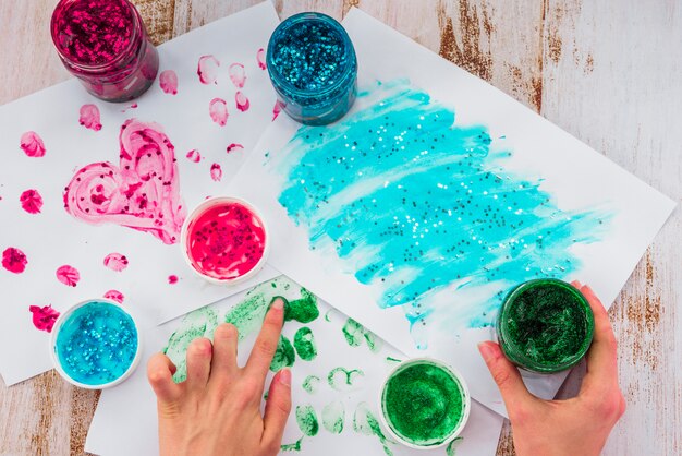 Primer plano de la mano de una persona que pinta con los dedos usando color glitter