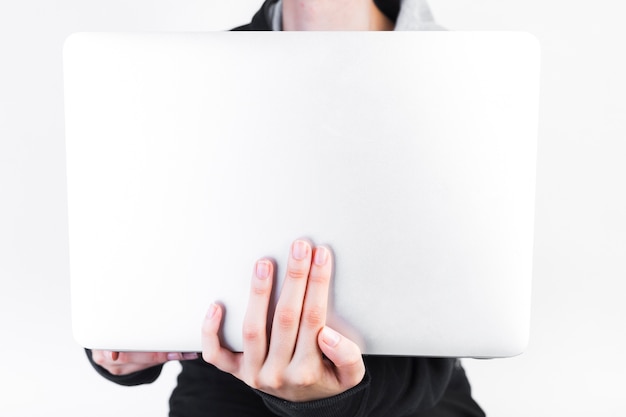Primer plano de la mano de una persona que sostiene la computadora portátil