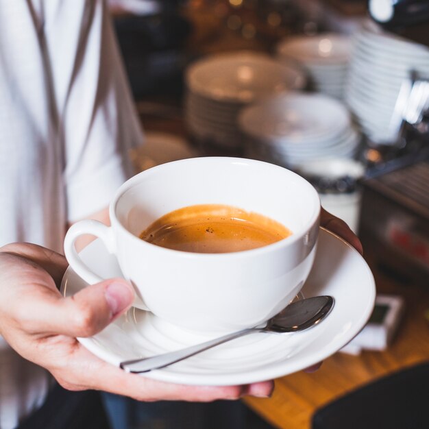 Primer plano de la mano de la persona que sostiene la deliciosa taza de café