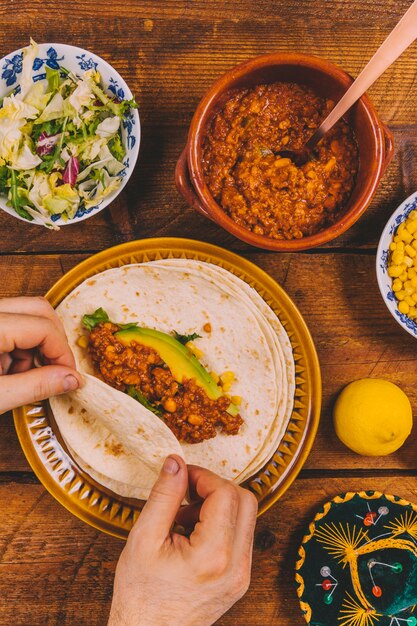 Primer plano de la mano de las personas preparando tacos de carne de res