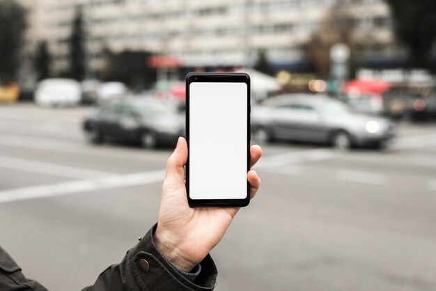 Primer plano de la mano que muestra la pantalla del teléfono inteligente en la carretera