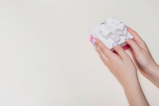 Primer plano de la mano que sostiene la caja de regalo sobre fondo blanco