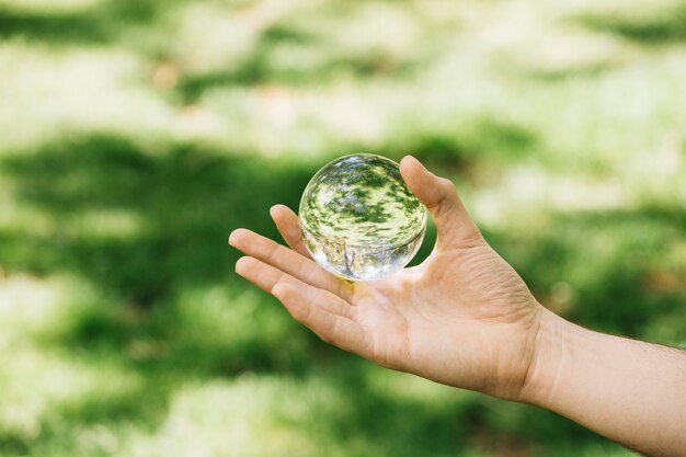 Primer plano de la mano que sostiene la esfera transparente al aire libre