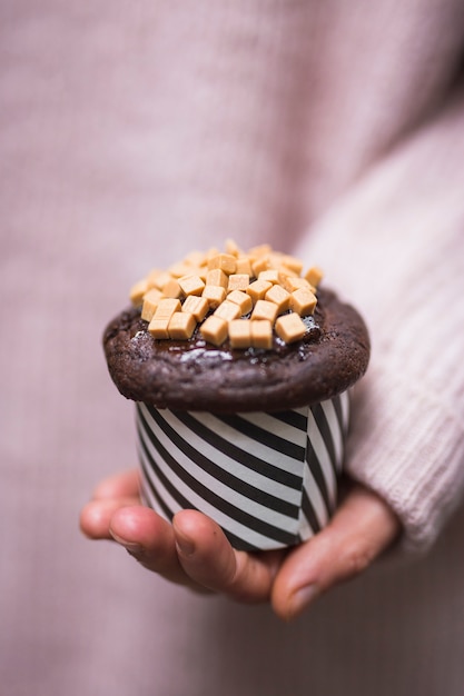 Foto gratuita primer plano de la mano que sostiene la magdalena con coberturas de dulce de azúcar caramelo