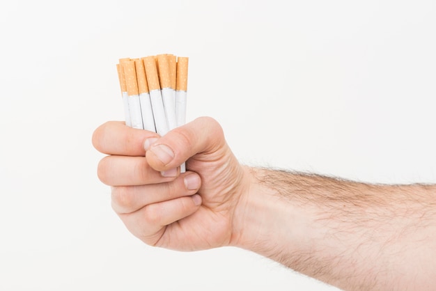 Foto gratuita primer plano de la mano que sostiene la pila de cigarrillos contra el fondo blanco