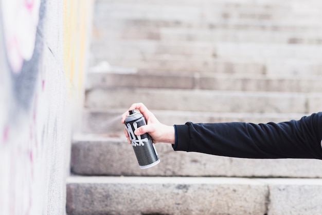 Primer plano de una mano que sostiene la pintura en aerosol para el arte de la calle