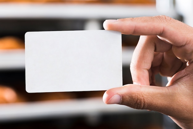 Primer plano de la mano que sostiene la tarjeta de visita rectangular blanco en blanco