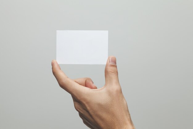 Primer plano de una mano sosteniendo un papel en blanco