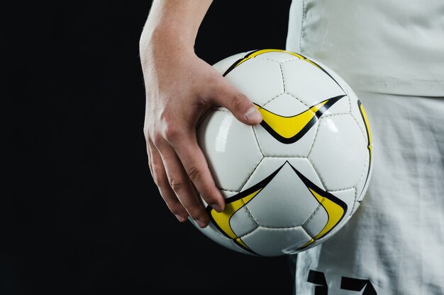 Primer plano de mano sujetando un balón de fútbol