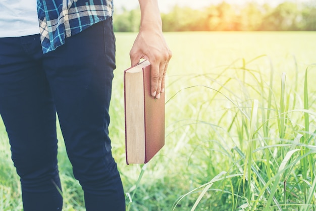 Primer plano de mano sujetando un libro al aire libre