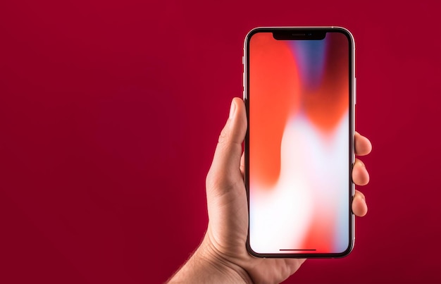 Foto gratuita primer plano mano sujetando teléfono móvil en fondo rojo liso