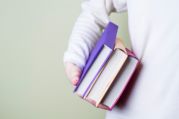 Primer plano de mano sujetando tres libros de colores