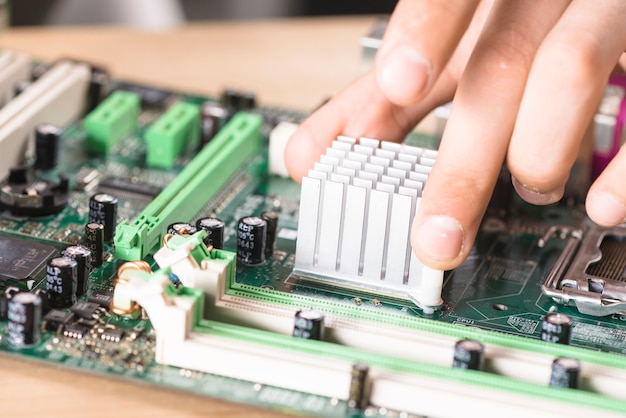 Primer plano de la mano del técnico masculino que instala el disipador térmico en el tablero principal de la computadora