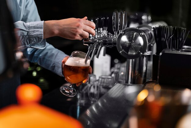 Primer plano mano vertiendo cerveza en vidrio