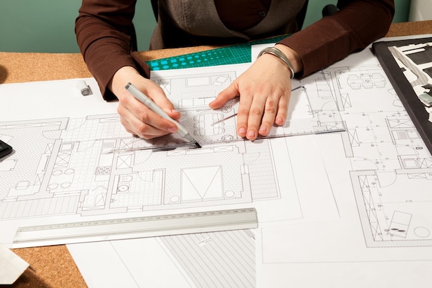 Primer plano de las manos del arquitecto trabajando en planos. Diseño y sartén. Dibujo profesional de planos de arquitecto