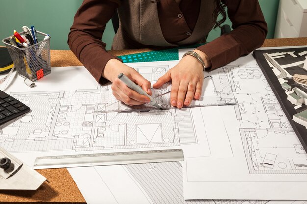 Primer plano de las manos del arquitecto trabajando en planos. Diseño y sartén. Dibujo profesional de planos de arquitecto