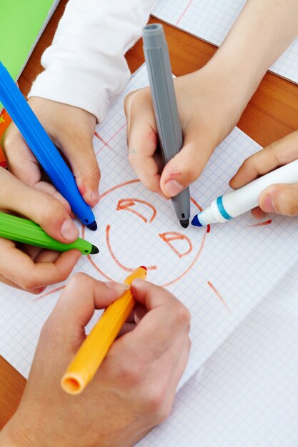 Primer plano de manos dibujando con rotuladores de colores