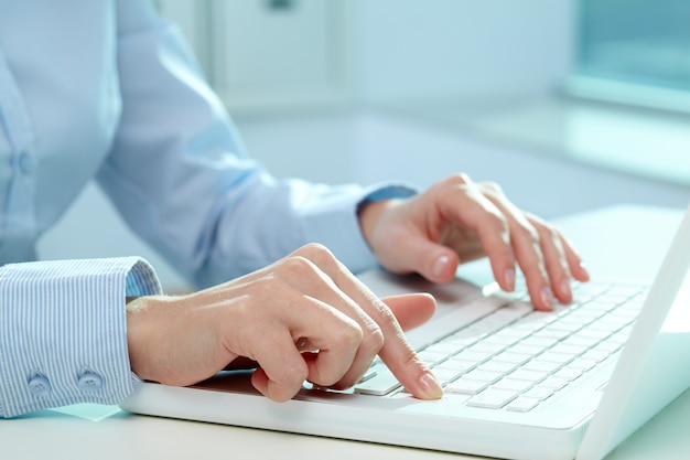 Primer plano manos de una empresaria escribiendo en el teclado