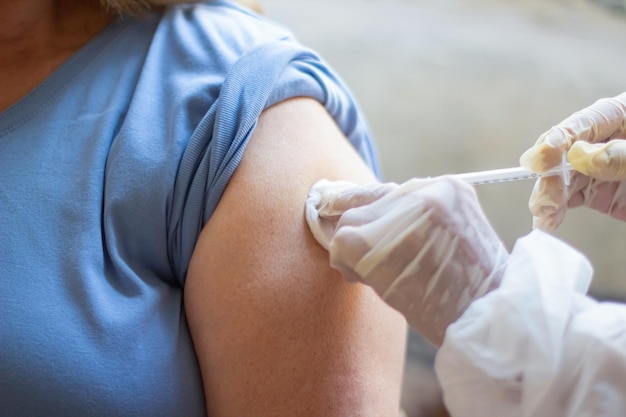 Primer plano de las manos de la enfermera vacunando al paciente con jeringa. Doctor inyectando la parte superior del brazo del paciente. Medicina, vacunación, inmunización, concepto de salud.