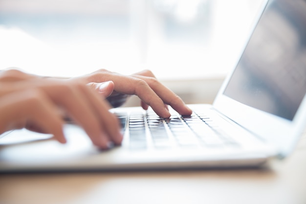 Primer plano de las manos escribiendo en el teclado portátil masculina