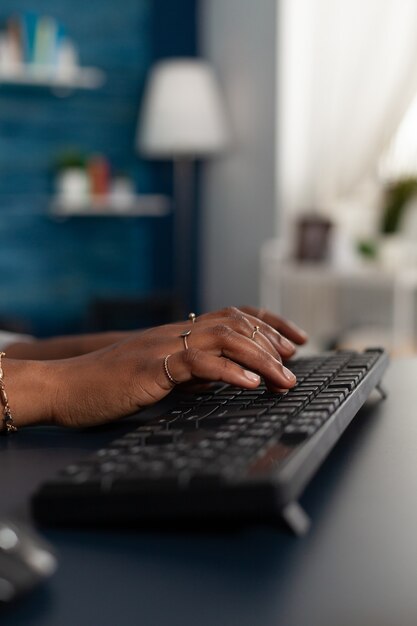 Primer plano de las manos del estudiante negro escribiendo información educativa en el teclado