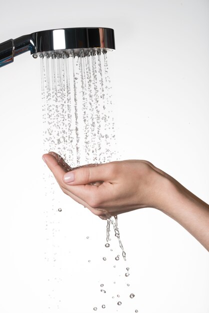 Primer plano de las manos femeninas bajo el chorro de agua de la ducha - concepto de cuidado de la piel