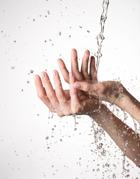Primer plano manos femeninas bajo el chorro de agua salpicando