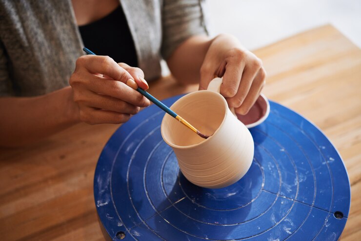 Foto gratuito primer plano de manos femeninas decorando una taza de arcilla hecha a mano