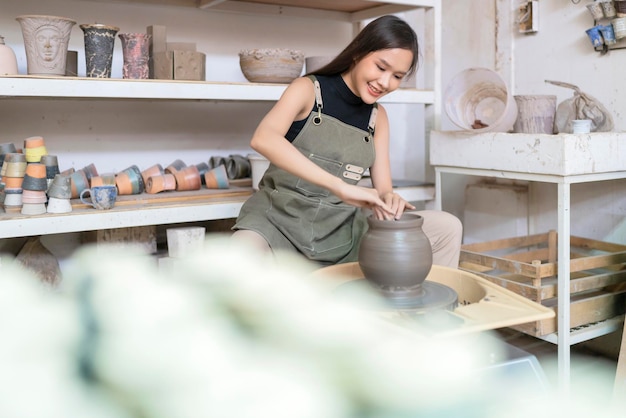 Primer plano de las manos femeninas que trabajan en alfareros rueda escultura femenina asiática mujer formando molde pequeño jarrón tazón de arcilla en la rueda de alfarero en casa estudio taller arte y creación hobby concepto