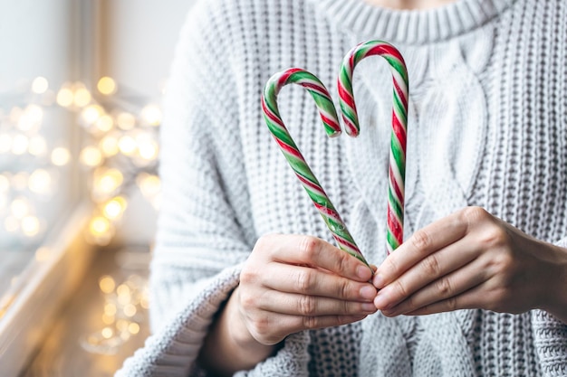 Foto gratuita primer plano de manos femeninas sosteniendo bastones de caramelo en forma de corazón