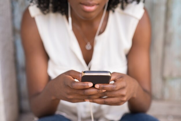 Primer plano de las manos femeninas con teléfono inteligente al aire libre