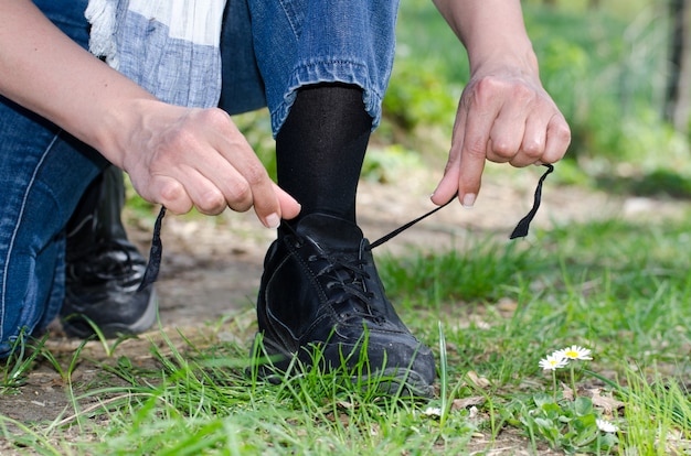 Primer plano de las manos de un hombre atando sus cordones en el campo cubierto de hierba