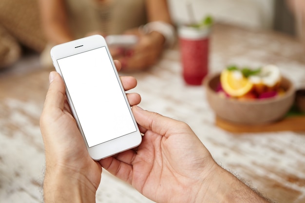 Primer plano de las manos del hombre sosteniendo el teléfono celular con pantalla de espacio de copia en blanco para su texto.